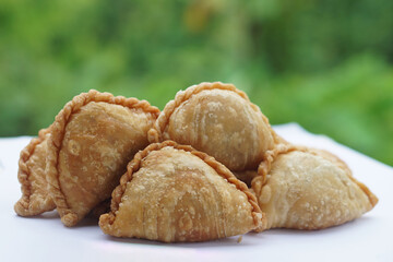Homemade crispy golden brown curry puffs or karipap in Thai. Concept, traditional snack. A beloved savory pastry filled with spiced fillings, perfect for tea time or festive gatherings.            