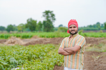 young indian farmer standing confidently at green agricultural field