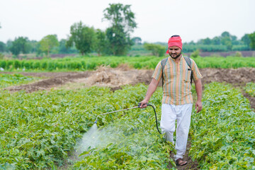 indian farmer spraying pesticide at green field © stockimager