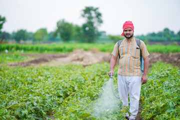 indian farmer spraying pesticide at green field