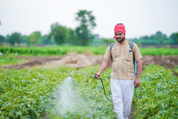 indian farmer spraying pesticide at green field © stockimager