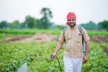 indian farmer spraying pesticide at green field