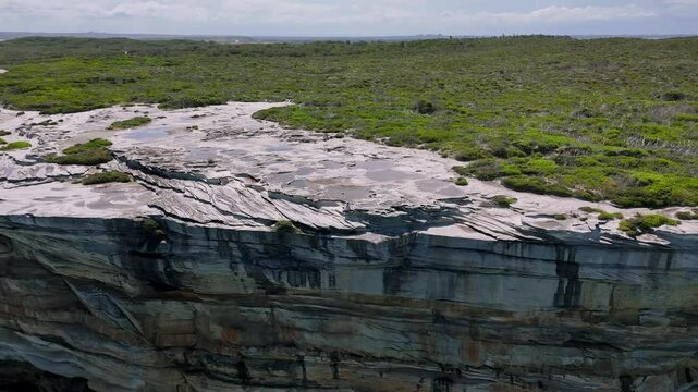 Kurnell, Sydney, Australia-UHD Drone Video: Spectacular view from above of waves splashing on the sandstone cliffs of the coast, on the scenic Cape Baily Track and Lighthouse in Kamay National Park.
