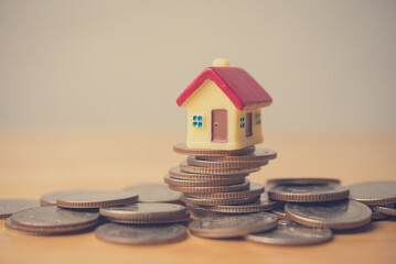 House on stack coins crash on wooden table with white background copy space. Risk and financial management, economy crisis, foreclosure, asset forfeiture, unable paying mortgage loan, banking concept.