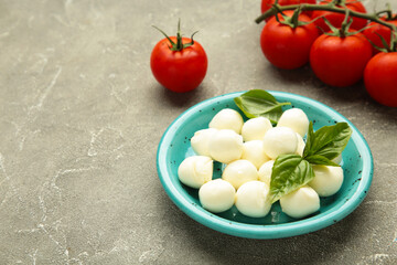 Italian Caprese salad with cherry tomatoes, mozzarella, basil on plate on grey concrete background.