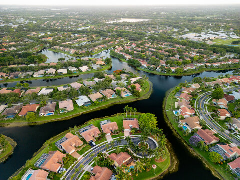 Aerial view of winding waterways reflect the sky amidst residential communities dotted with lush green trees, Weston, Florida, United States.
