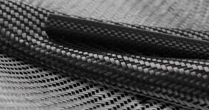 Carbon fabric and a carbon tube in close-up on a rotating table. Raw materials for carbon production.