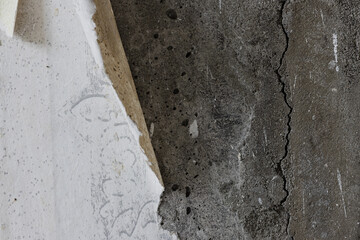 Torn old faded paper wallpaper with a retro pattern. Tattered scraps of paper on a concrete wall. Vintage texture for background and design. Closeup view with copy space. High resolution.