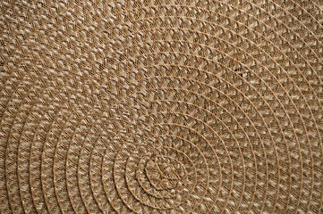 Close up of a woven seashore mat on a black table, shown from above.