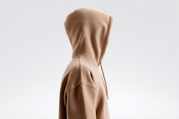 Neutral hoodie fashion: Faceless figure in a minimalist tan hoodie, blending style with anonymity on a seamless white background.