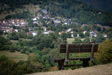 Wooden Bench Overlooking Scenic Village with Rolling Hills and Forested Backdrop
