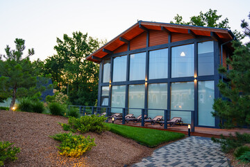 Half-timbered country house with glass walls and sunbeds.