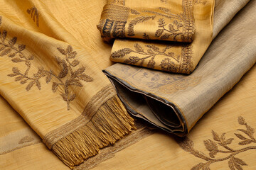 Rich golden yellow fabric featuring intricate embroidery with decorative edges, showcasing...