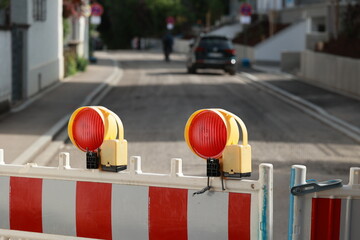 Red and white striped barrier with two red lights on top
