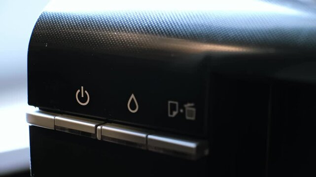The printer has a green indicator light and an orange warning light indicating a technical malfunction. Out of ink, stuck or out of paper, printing error. Person presses a button turning off a device.