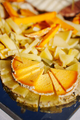 banquet table with appetizers. In the foreground is a plate of sliced cheese