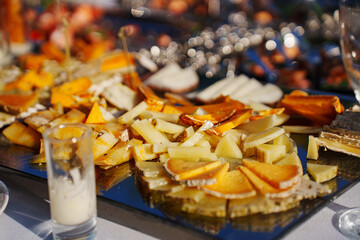 banquet table with appetizers. In the foreground is a plate of sliced cheese