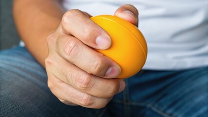 A hand gripping a bright yellow stress ball, showcasing a relaxed and focused moment in daily life.