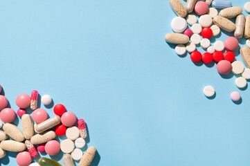 Different multi-colored tablets, vitamins, pills on blue background close-up. Concept of health and...