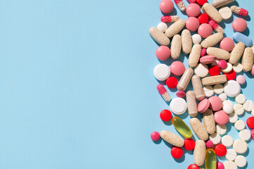 Different multi-colored tablets, vitamins, pills on blue background close-up. Concept of health and...