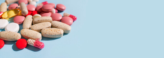 Different multi-colored tablets, vitamins, pills on blue background close-up. Concept of health and medicine, healthcare and pharmacology. Dietary supplements and homeopathy background