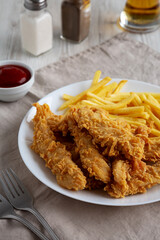 Homemade Chicken Strips with Fries on a Plate, side view.