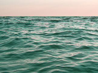 Sea and rocks into the pink sunset. Waterscape. Blue water background. Sea layout. Seawater...
