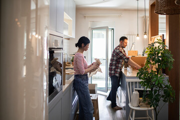 Couple unpacking boxes and organizing kitchen after moving into new home
