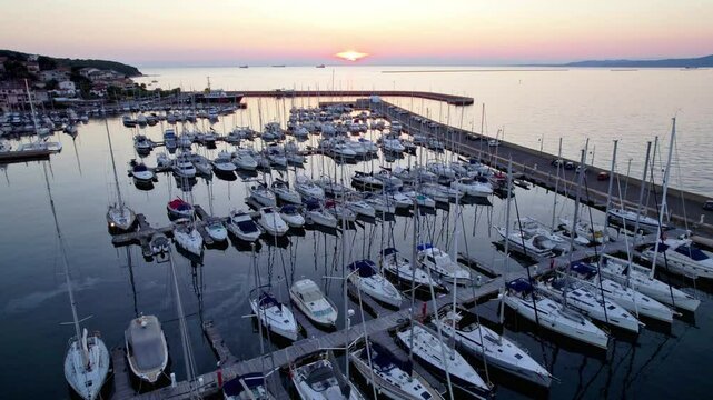 Boats parked in an Italian marina during a beatiful colorful sunset, drone shot UHD