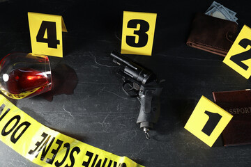 Forensic expert. Yellow crime scene tape, markers and evidences on black table, above view