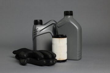 Motor oil in plastic canisters, gloves and filter on grey background