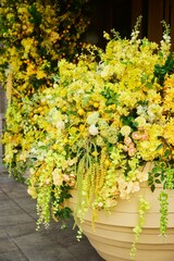Various types of artificial plants in yellow shades as a decoration for the entrance to a store or hotel