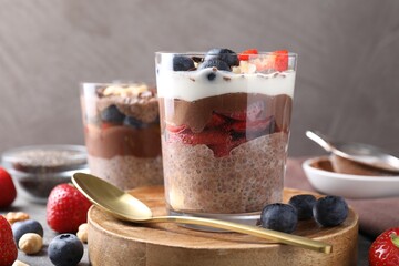Delicious chocolate pudding with chia seeds, berries and hazelnuts in glasses on table, closeup