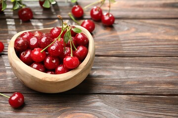 Fresh wet cherries in bowl on wooden table, closeup. Space for text