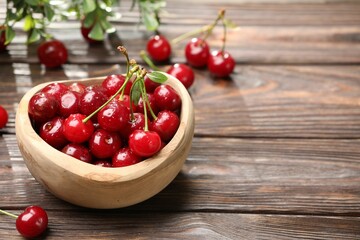 Fresh wet cherries in bowl on wooden table, closeup. Space for text