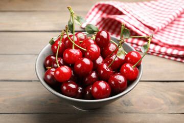 Fresh wet cherries in bowl on wooden table, closeup