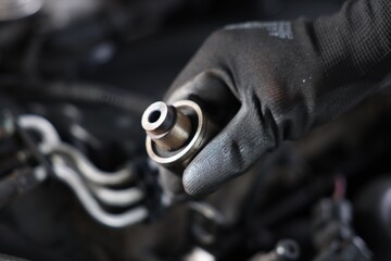 Auto part. Professional mechanic with bearings near open hood of car indoors, closeup. Space for...