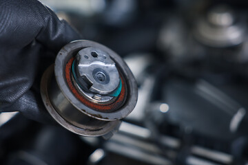 Auto part. Professional mechanic with idler-wheel near open hood of car indoors, closeup. Space for...