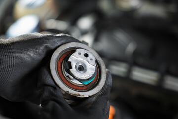 Auto part. Professional mechanic with idler-wheel near open hood of car indoors, closeup. Space for...