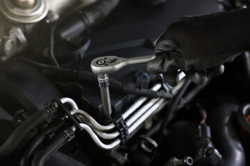 Auto parts. Professional mechanic with torque wrench fixing car indoors, closeup