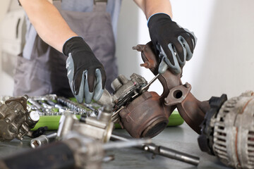 Auto parts. Professional mechanic with wrench fixing turbocharger at table indoors, closeup