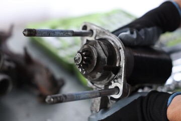Auto part. Professional mechanic with starter motor indoors, closeup