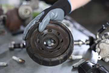 Auto part. Professional mechanic with strut mount at table indoors, closeup