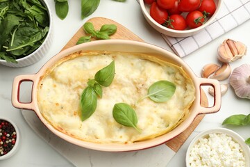 Tasty vegetarian lasagna and ingredients on white marble table, flat lay