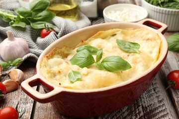 Tasty vegetarian lasagna and ingredients on wooden table, closeup