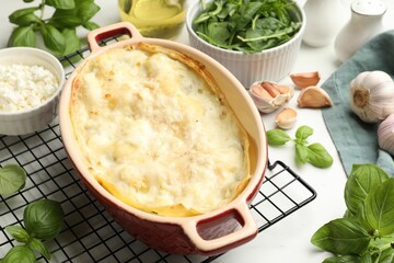 Tasty vegetarian lasagna and ingredients on white marble table, closeup