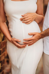 A man and a pregnant woman in white clothes on a walk.