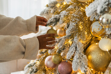 Merry Christmas. African American woman hands decorating Christmas tree. Girl near classical Christmas tree with white golden silver decorations ornament. Christmas eve at home time for celebration