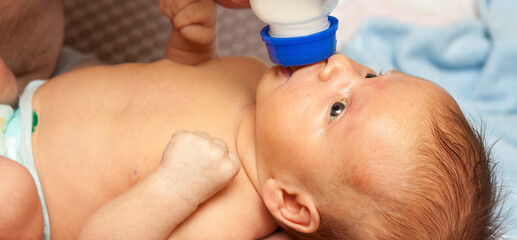 Newborn baby with jaundice sucks formula. Close-up portrait