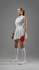 A confident female athlete gets ready to participate in a table tennis match, displaying focus and...
